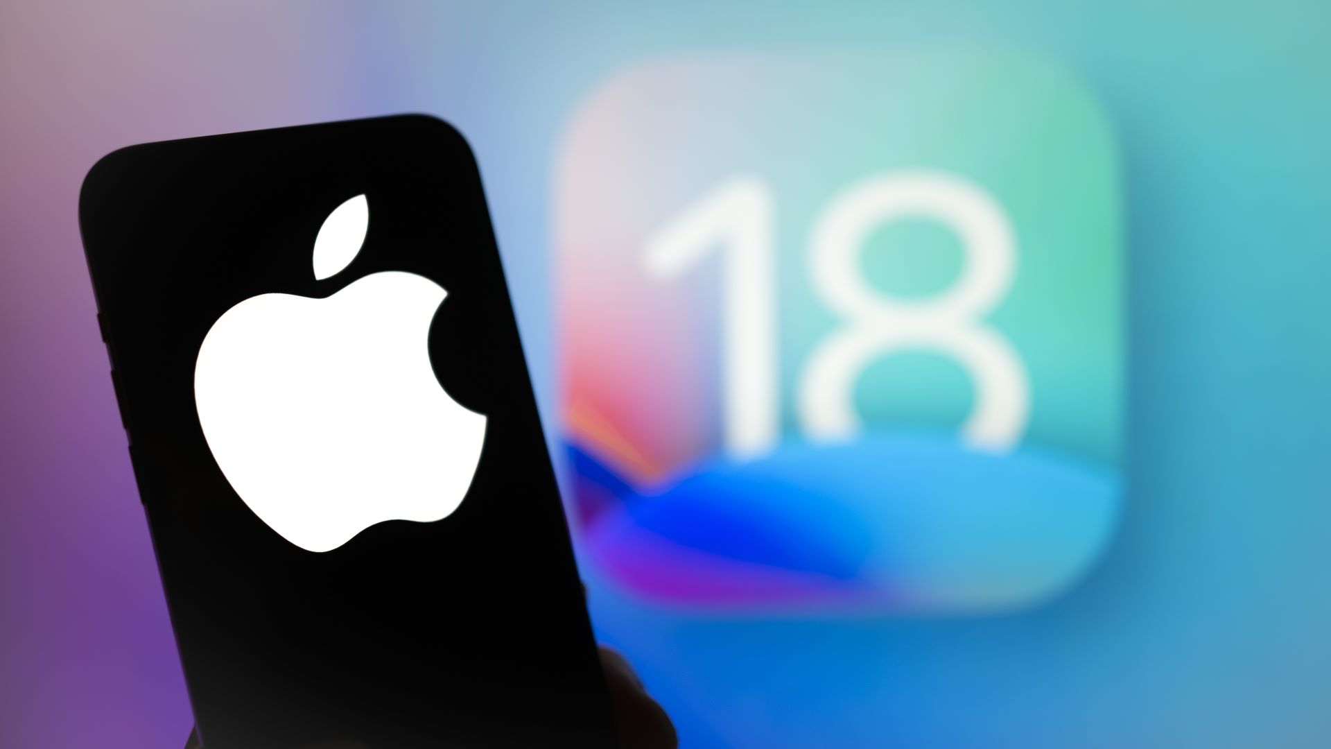 Das Apple -Logo wird mit dem iOS 18 -Betriebssystem -Logo im Hintergrund auf einem mobilen Gerät gesehen