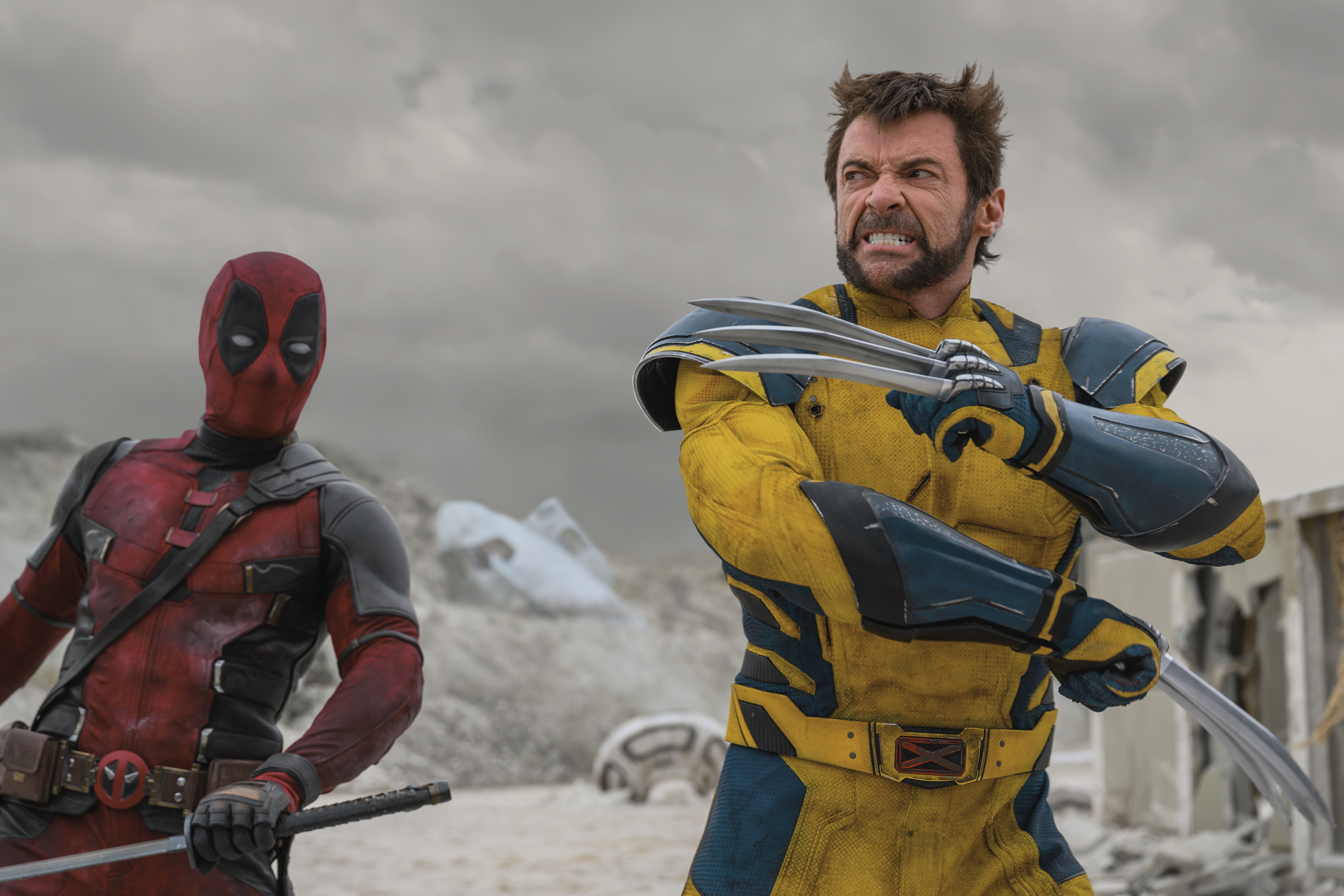 Wolverine knallt seine Krallen mit seinen Armen über die Brust, als Deadpool in einer Szene von Deadpool & Wolverine in Hand schaut, in Hand auf Schwert.