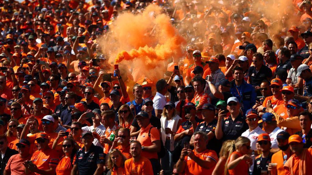Fans in orangefarbenen T-Shirts halten Fackeln im Duth Grand Prix in Zandvoort hoch 