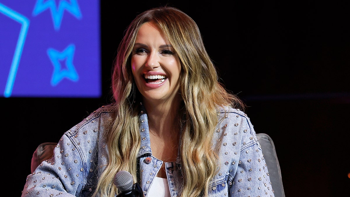 Carly Pearce lacht auf der Bühne in einer Jean -Jacke