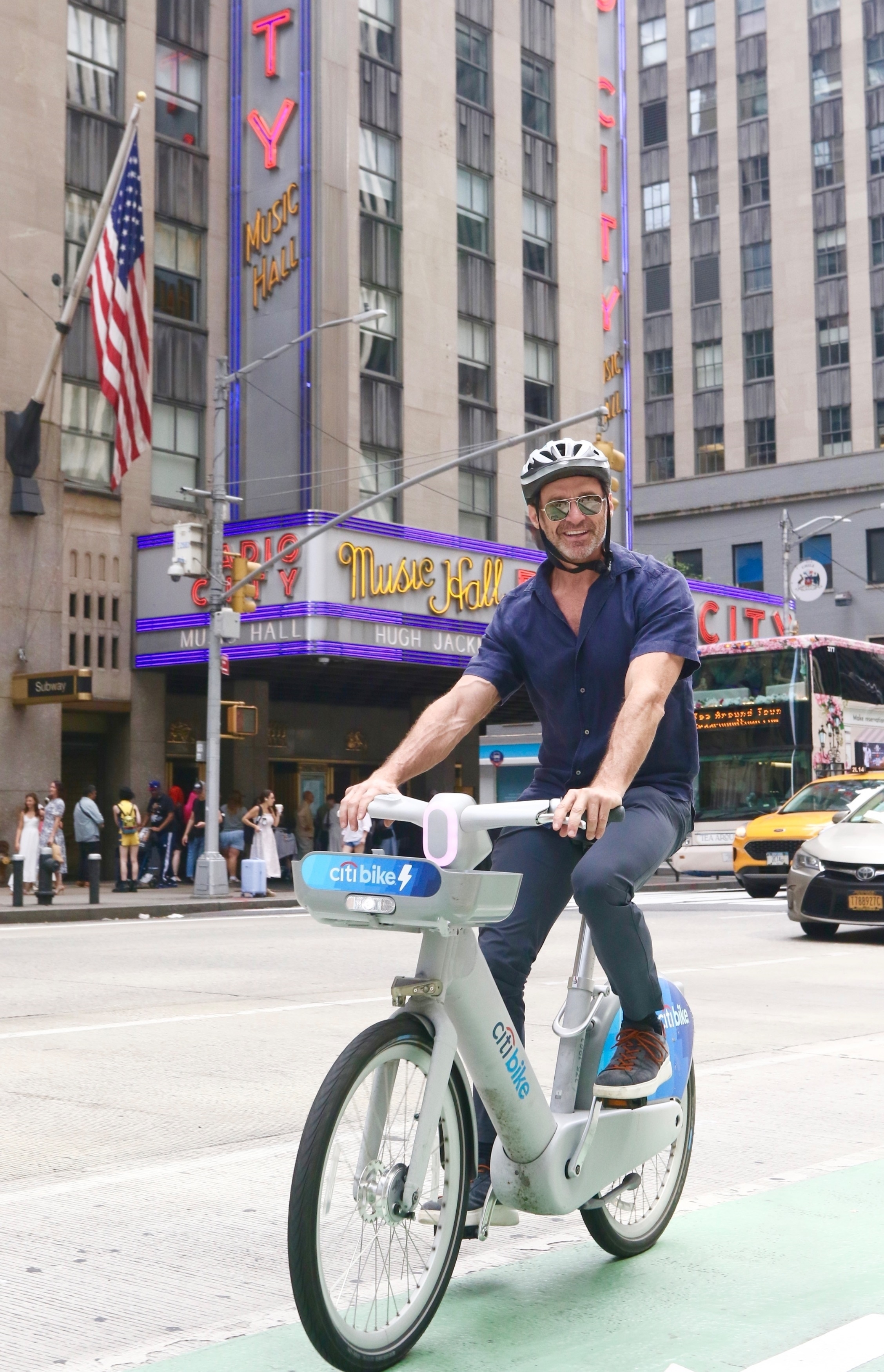 Hugh Jackman lächelt, als er eine Citibike von der Radio City Music Hall in NYC fährt.
