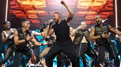 Getty Images Ricky Martin, der eine schwarze Weste trägt, tritt neben Backing -Tänzern auf