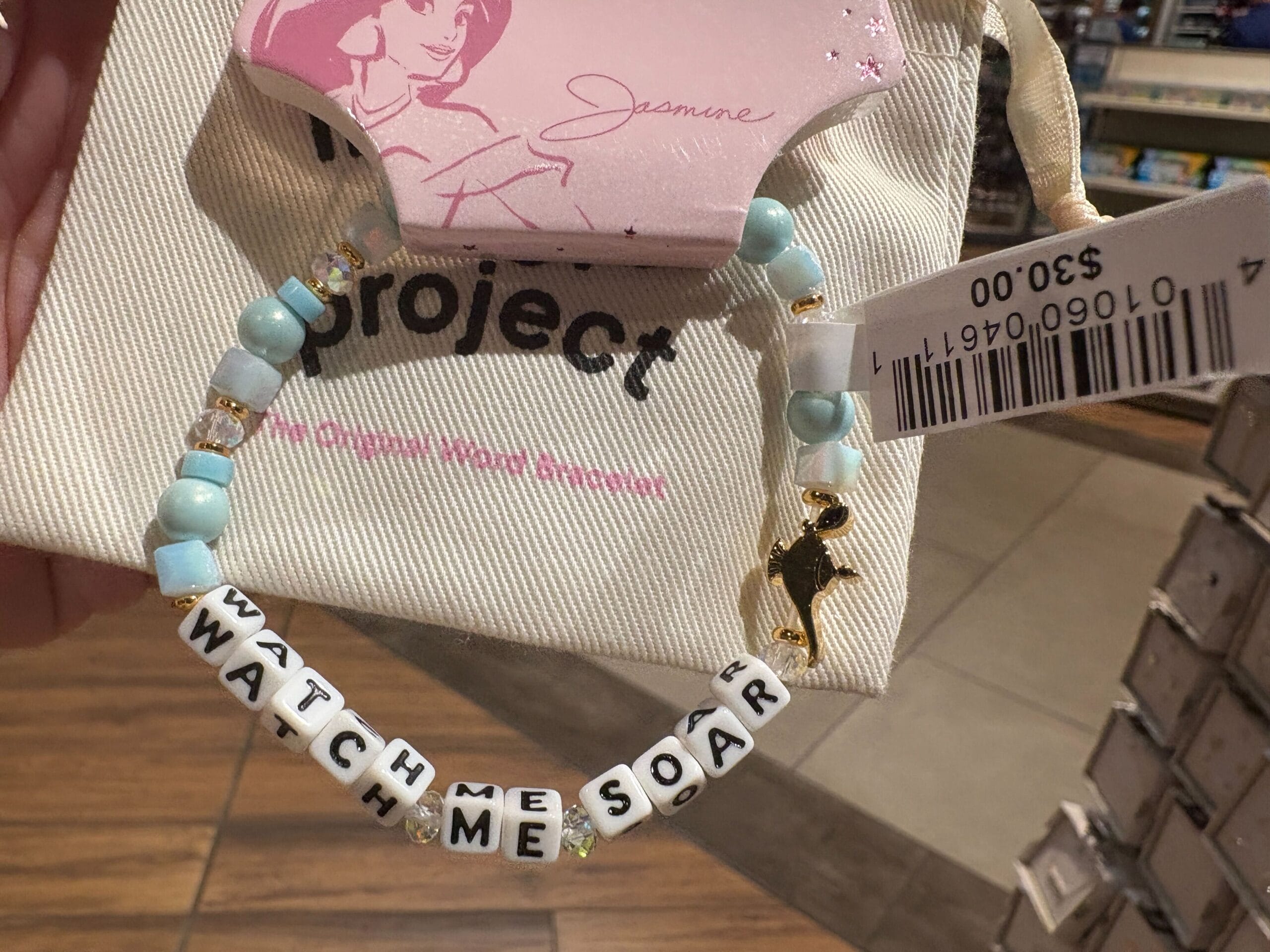 Ein Perlenarmbandzauber "Schau mich zu, wie ich aufgreift" Mit einem goldenen Vogelcharme, der in einem Geschäft mit einem Preis von 3 USD ausgestellt ist.